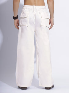 White cargo pants displayed folded, focusing on the smooth fabric and design details